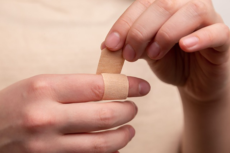 Lady applying a band aid on to index finger