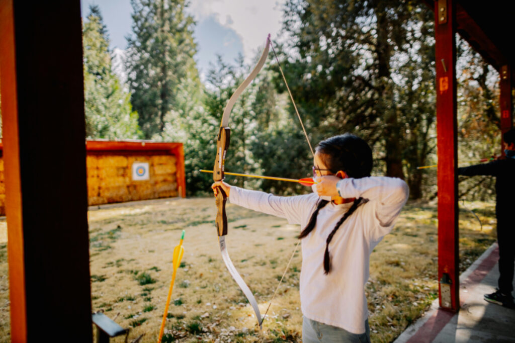 young girl pulling back a bow and arrow